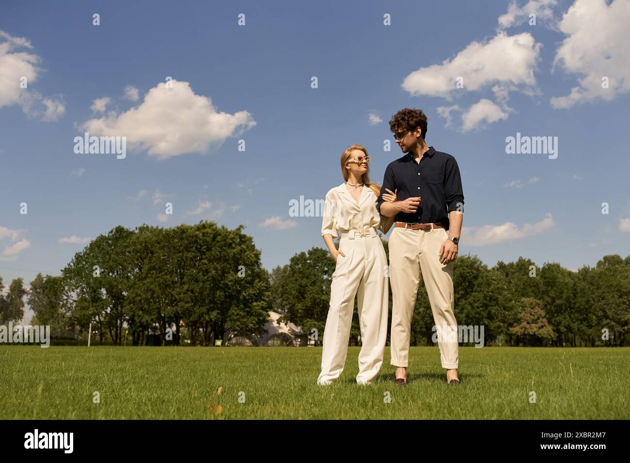 A stylish young man and woman clad in elegant attire are standing side ...
