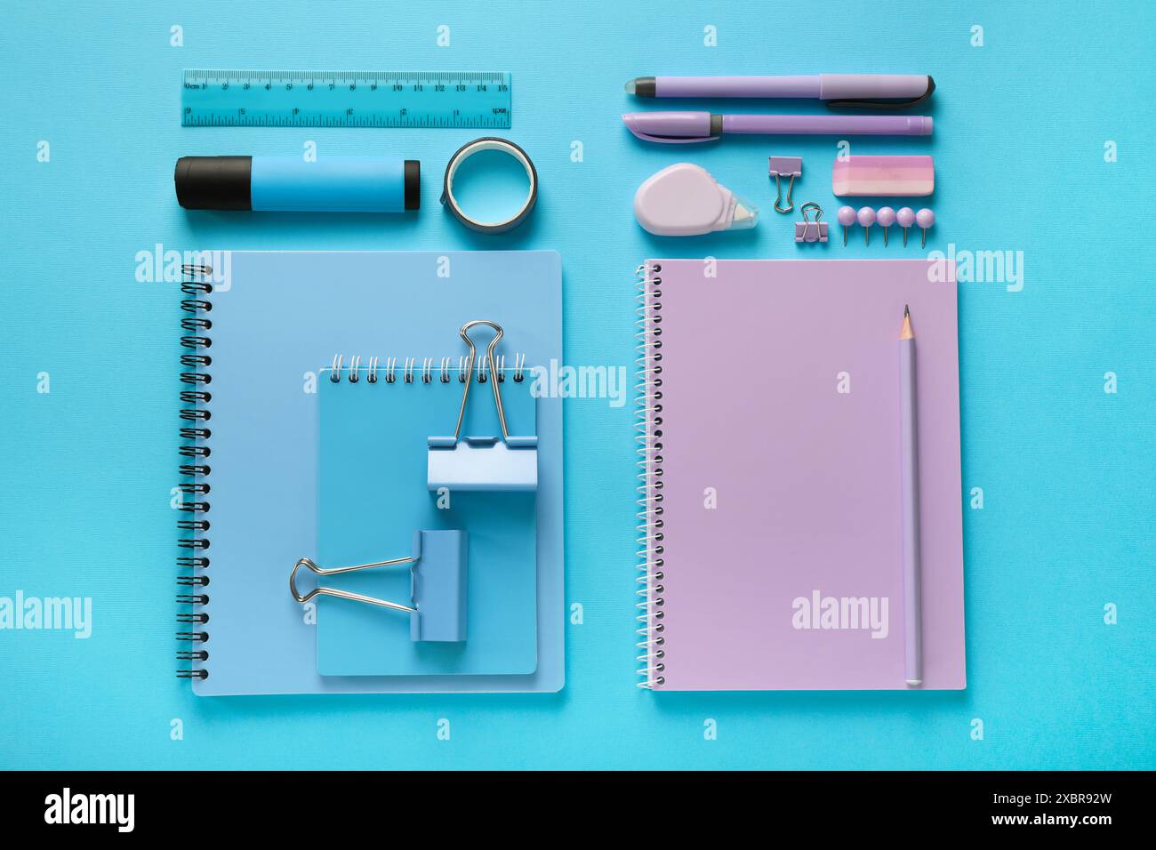 Flat lay composition with notebooks and different stationery on light blue background Stock Photo