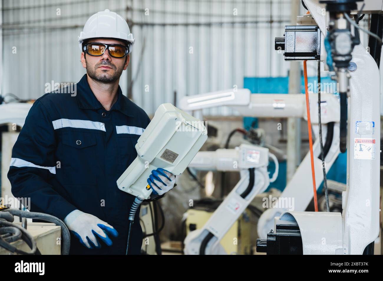 engineer controlling robot arm at factory. checking the operation of ...