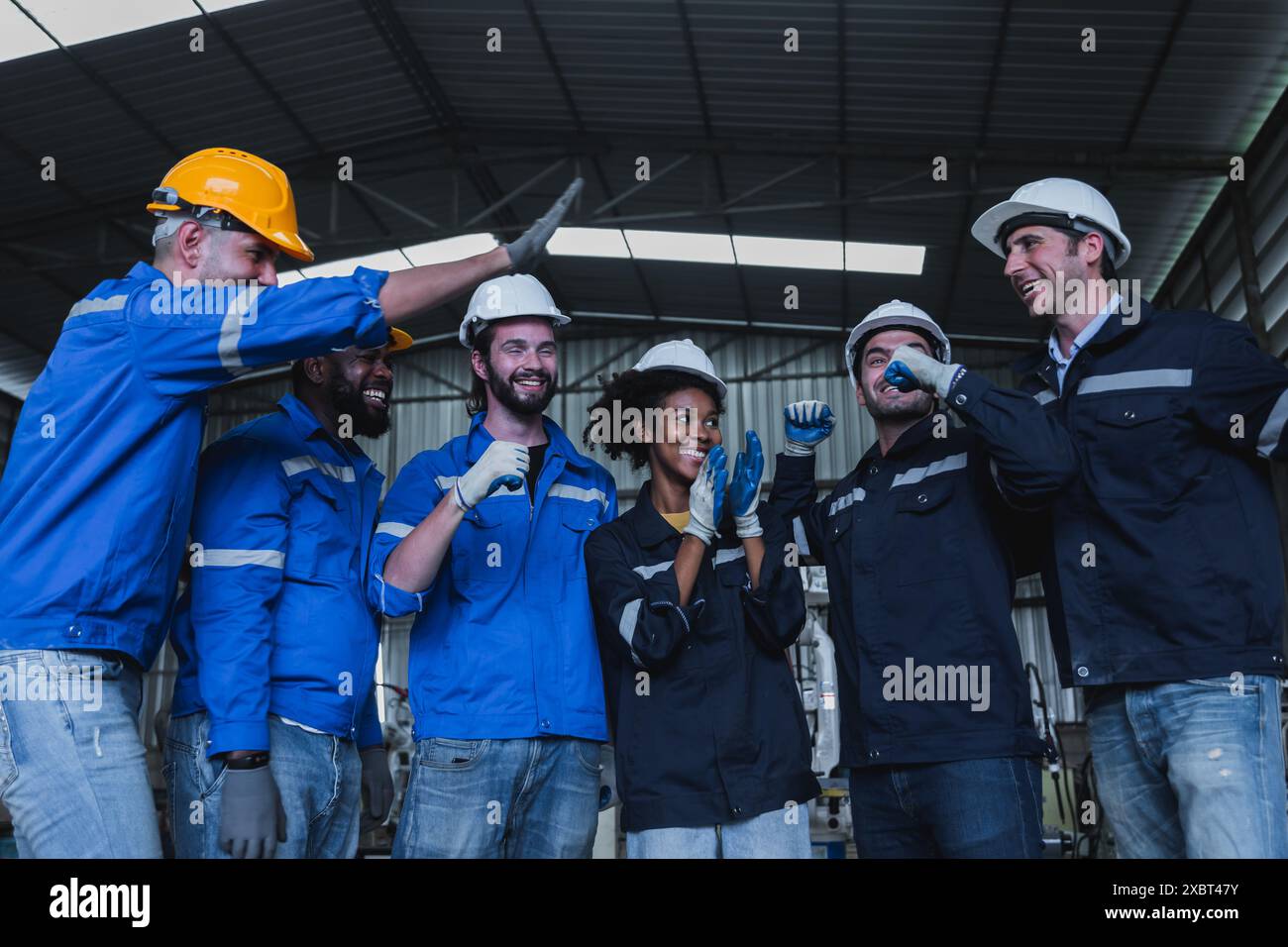 Team of successful group of male and female, corporate workers stand smiling together in industry factory Stock Photo