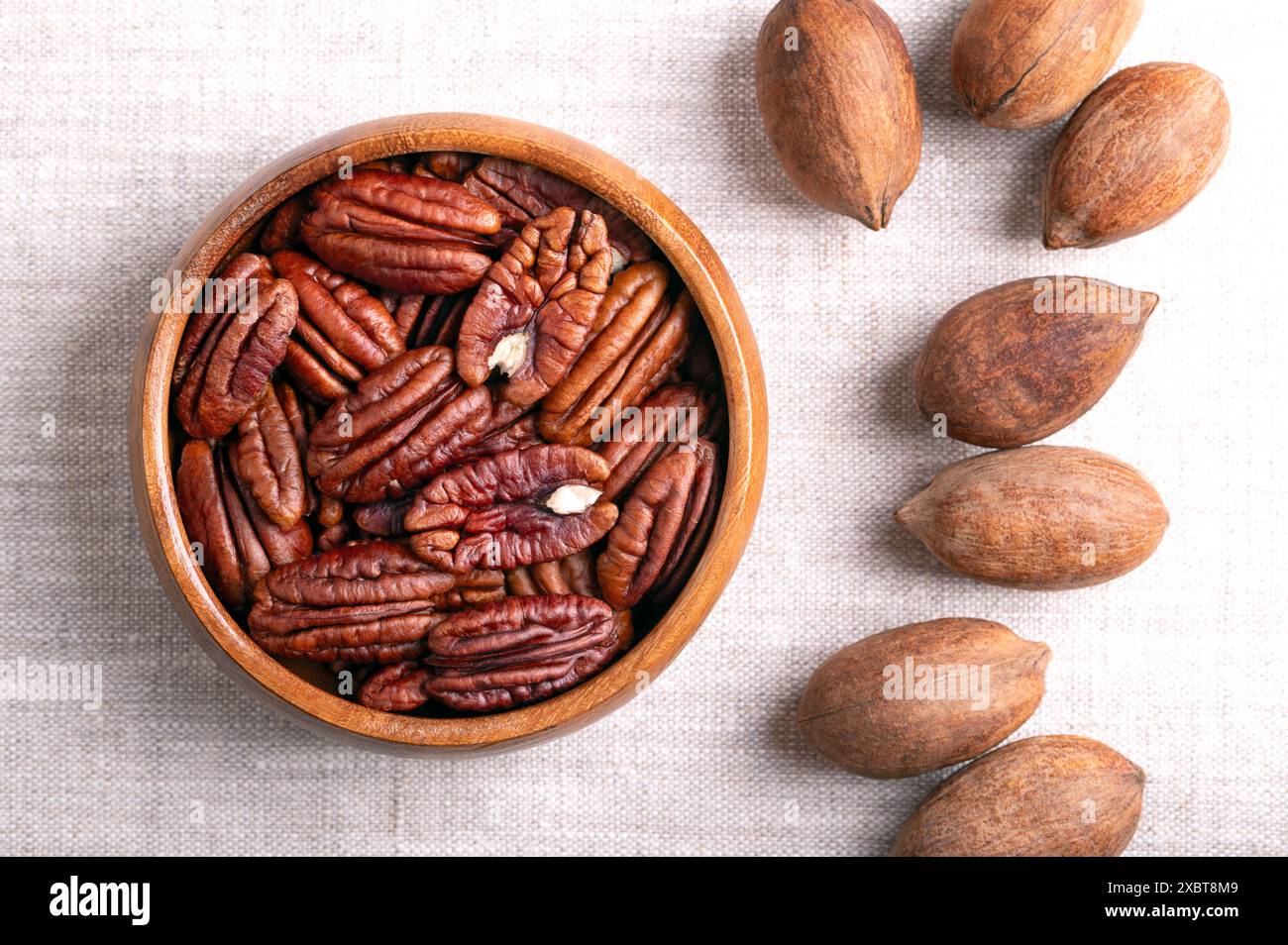 Pecan nuts in a wooden bowl on linen fabric. Dried pecan halves and ...