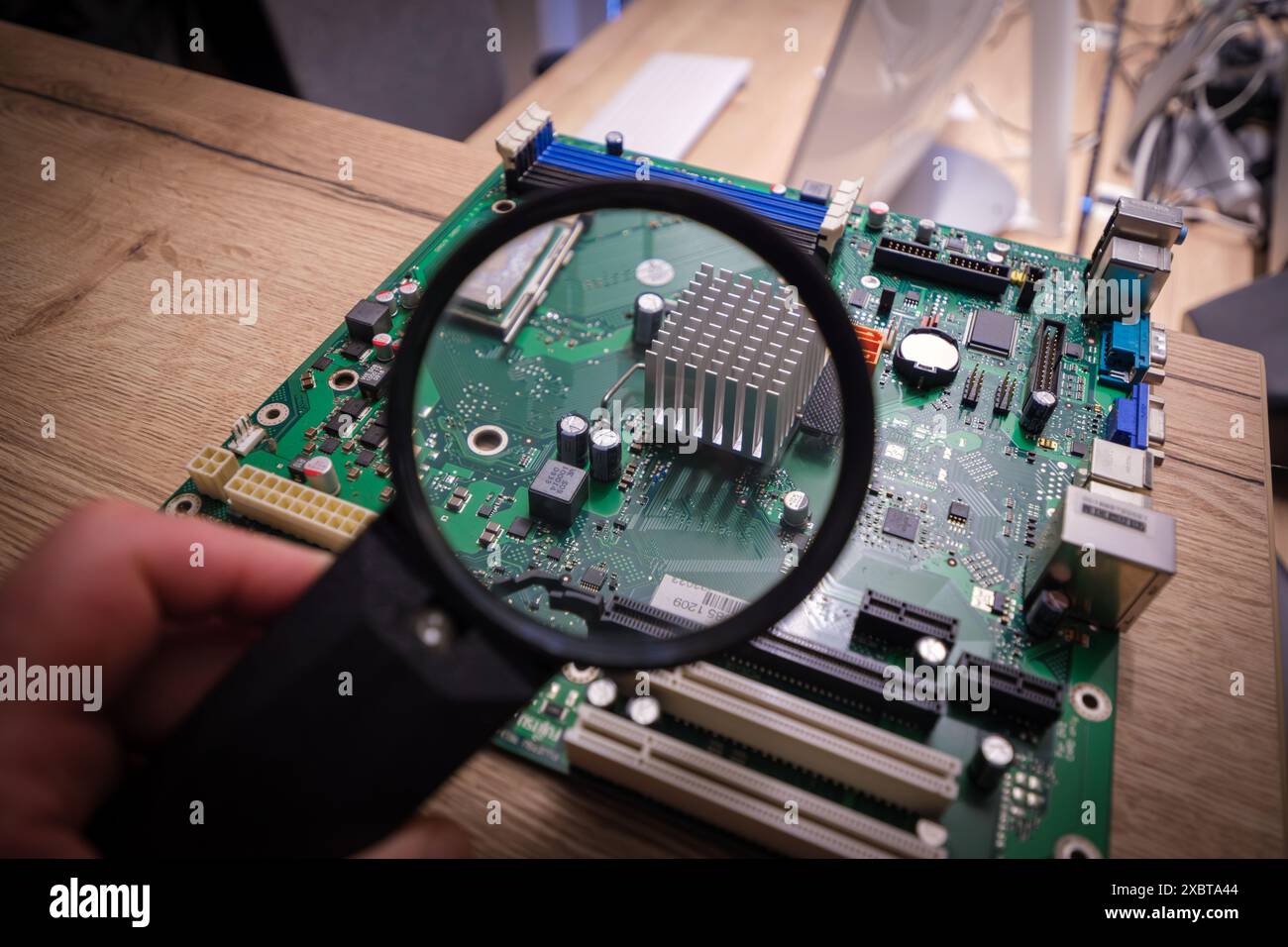 a computer mainboard is examined with a magnifying glass Stock Photo