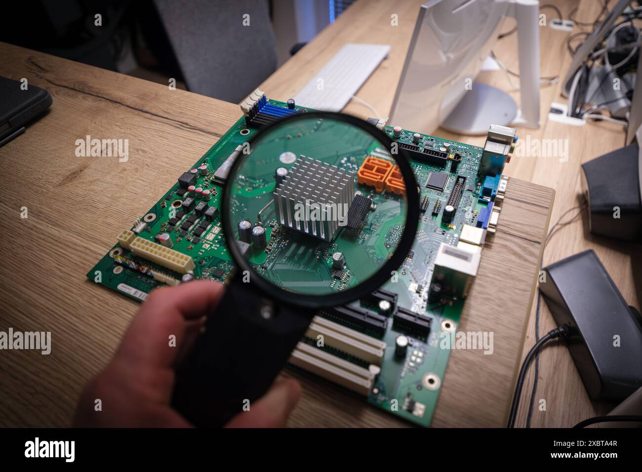 a computer mainboard is examined with a magnifying glass Stock Photo