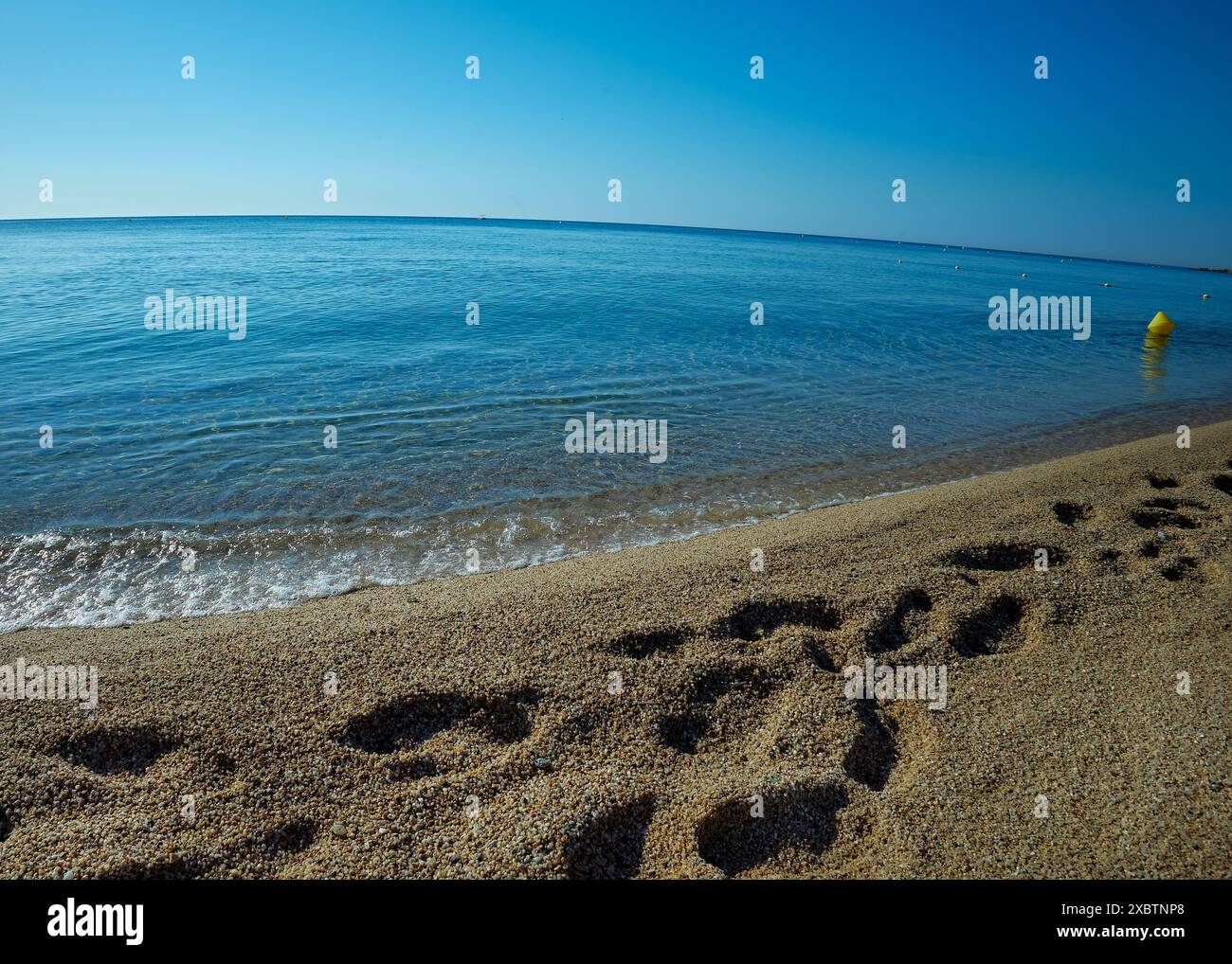 A strip of sea surf, coastal sand with footprints and horizont. Close- up, background. Stock Photo