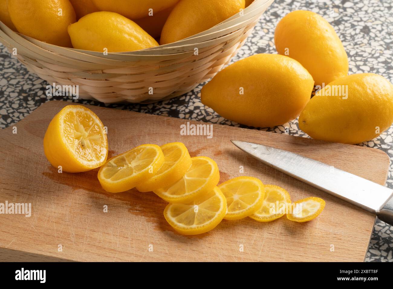 Sliced lemon snack on a cutting board close up and whole ons in the background Stock Photo