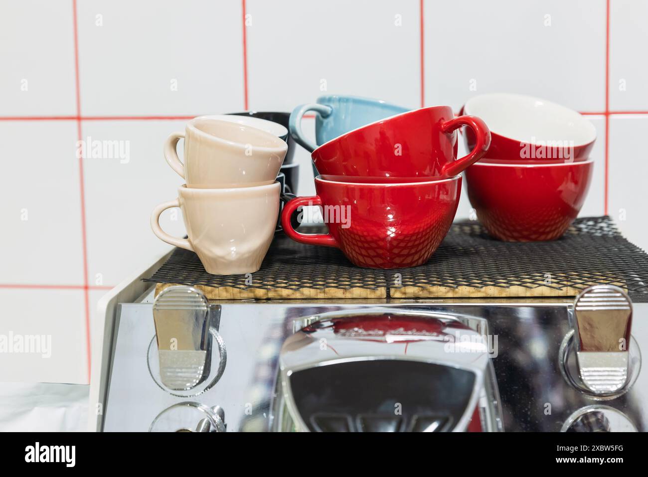 Bright colorful ceramic cups stand on the top of a coffee machine Stock Photo