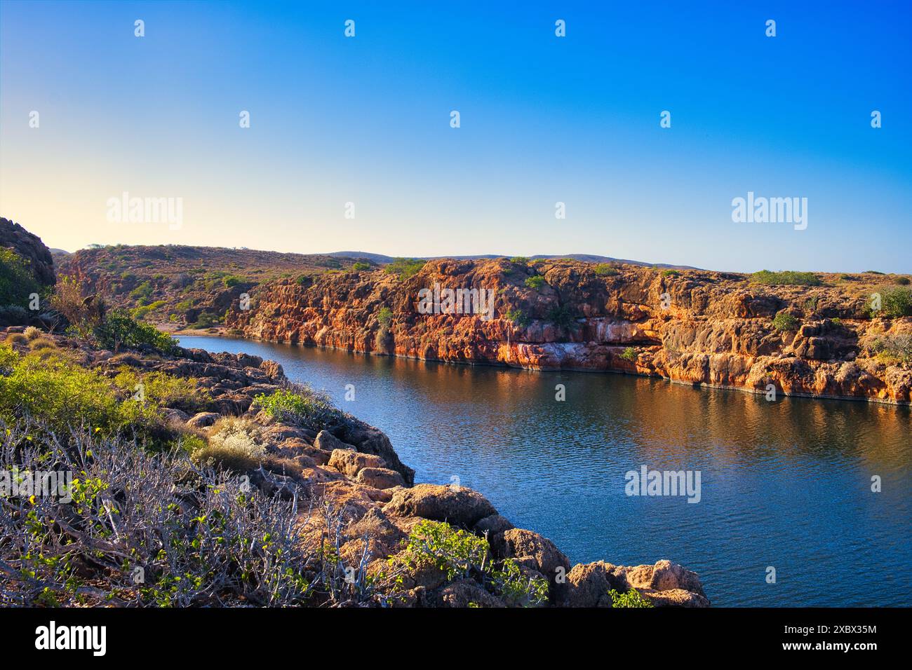 The gorge of the Yardie Creek in Cape Range National Park, Western Australia, with red limestone rocks and stunted outback vegetation Stock Photo