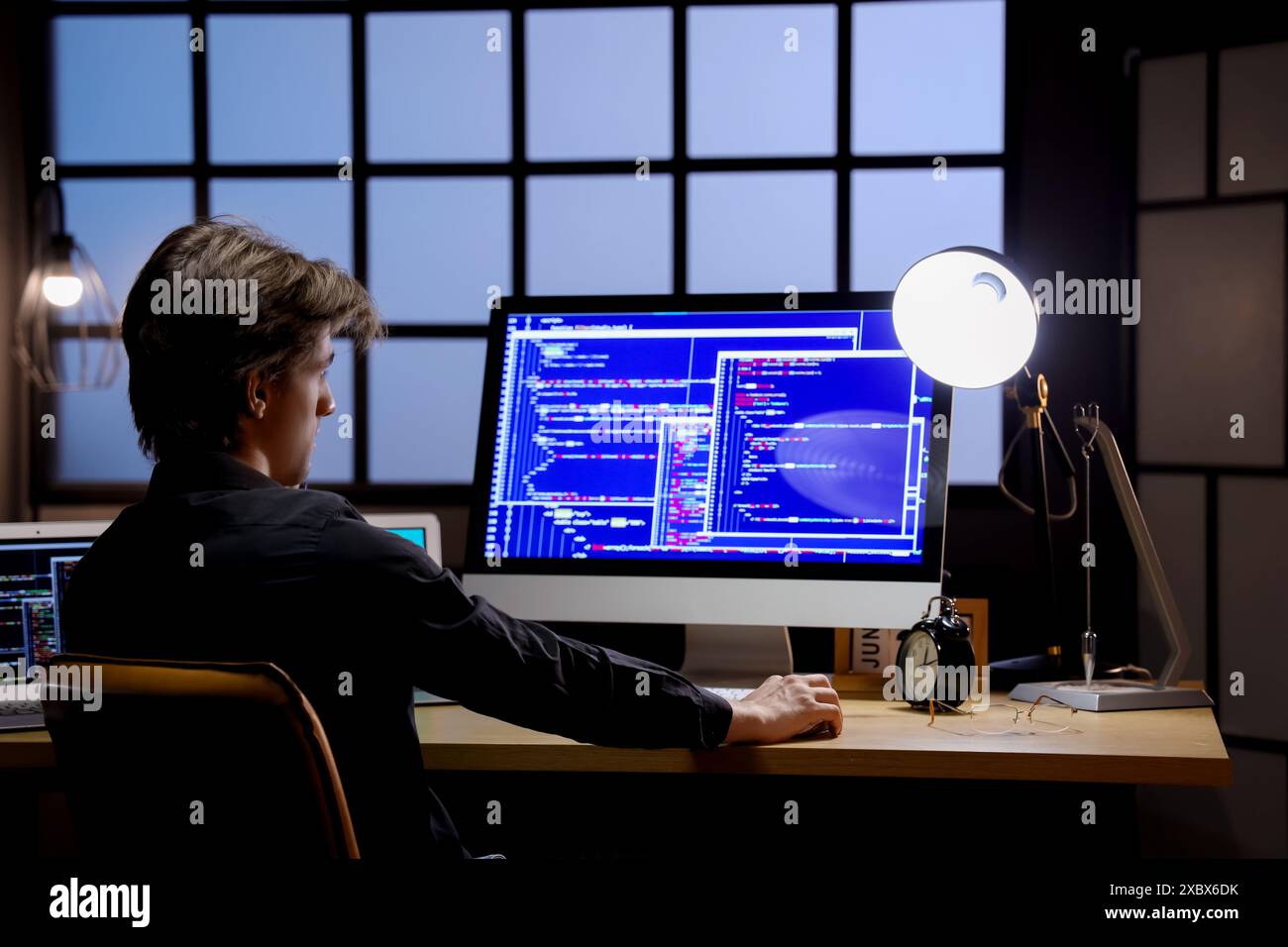 Young male programmer working with computers in office at night Stock Photo