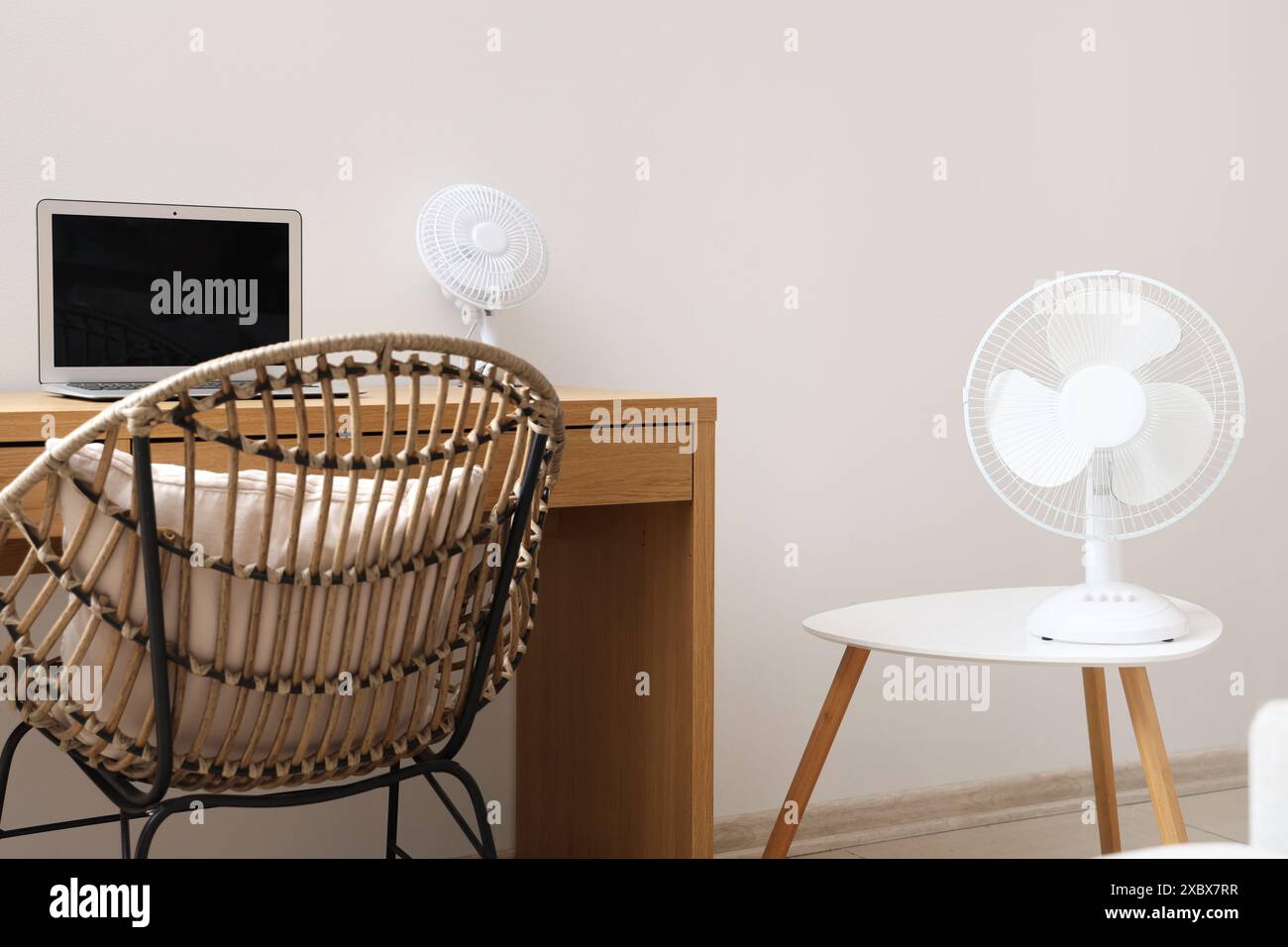 Modern electric fan and laptop on desk at home office Stock Photo - Alamy
