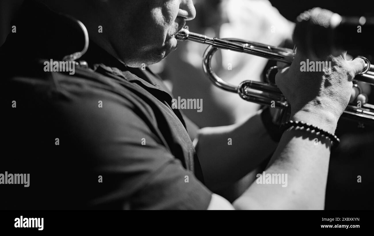 Close-up black and white shot of a musician playing the trumpet during a live performance. Stock Photo