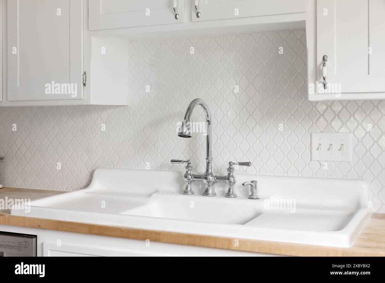 A kitchen faucet detail with a large white farmhouse sink with double