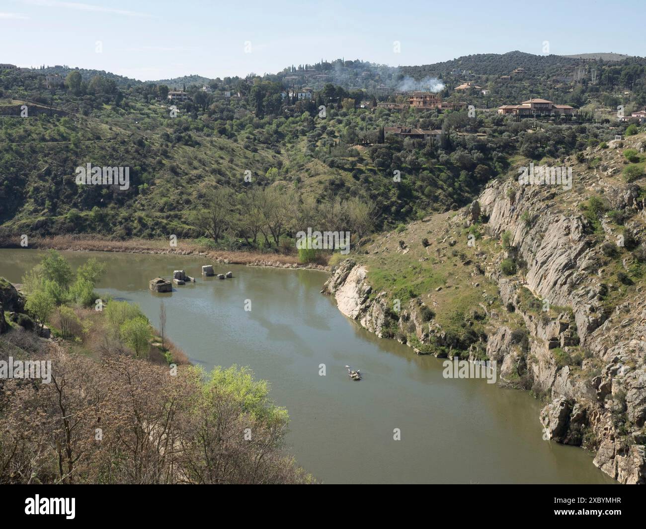A tranquil river meanders through a landscape surrounded by hills and ...
