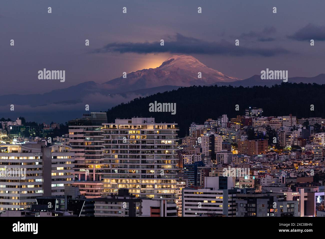 Resplandor de luz de la luna saliendo atrás del volcán Cayambe al anochecer Stock Photo