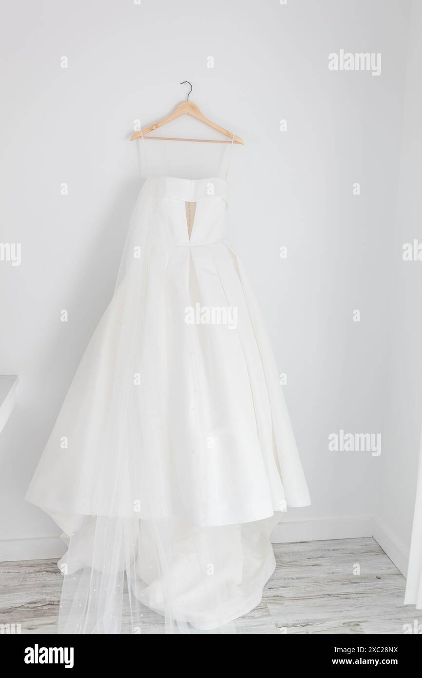 Wedding dress hanging on white wall Stock Photo - Alamy