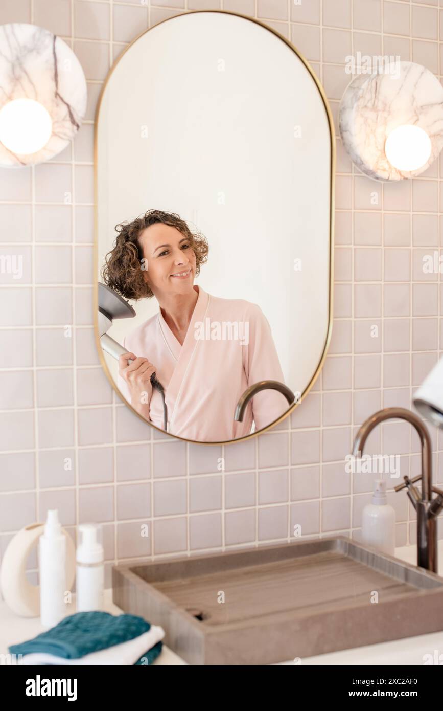 Women blow drying her hair in the mirror Stock Photo - Alamy