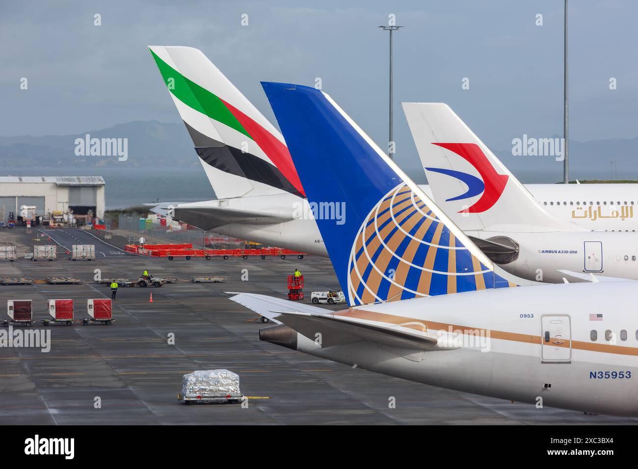 The tails and logos of (front to back) United Airlines, China Eastern, and Emirates planes at Auckland International Airport Stock Photo