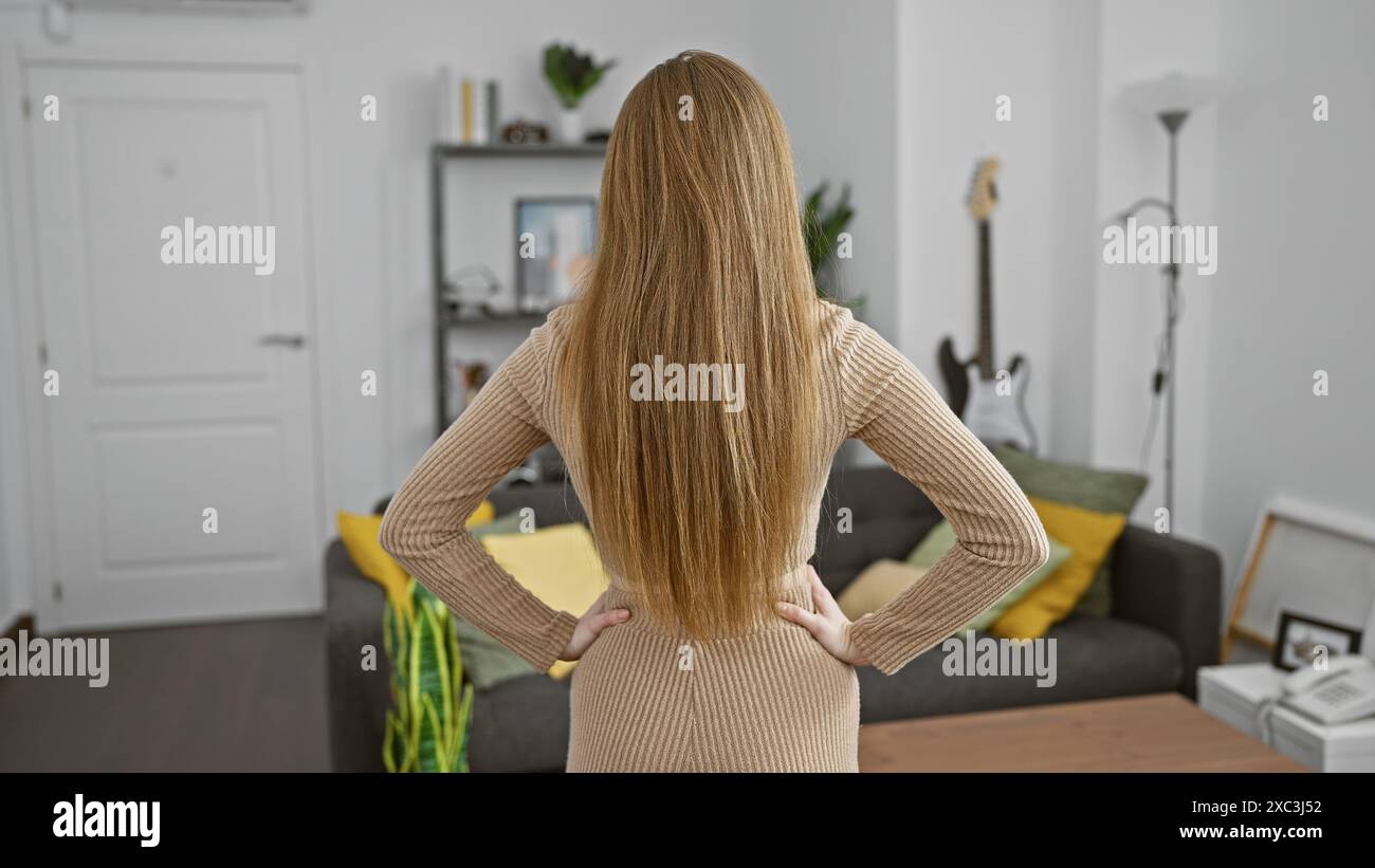 A young blonde woman stands with her back to the camera in a modern ...