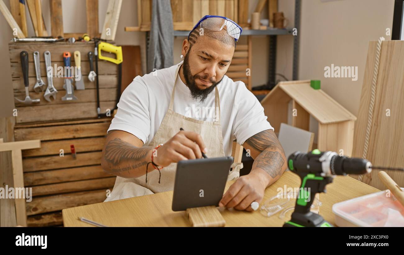Handsome bearded man using tablet in a well-equipped carpentry workshop Stock Photo