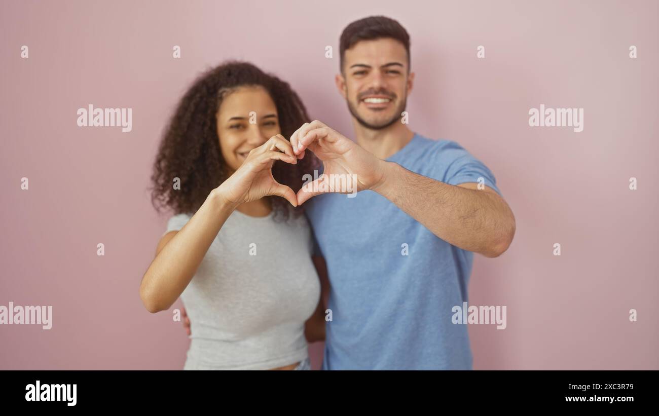 A smiling man and woman make a heart shape with their hands against a ...