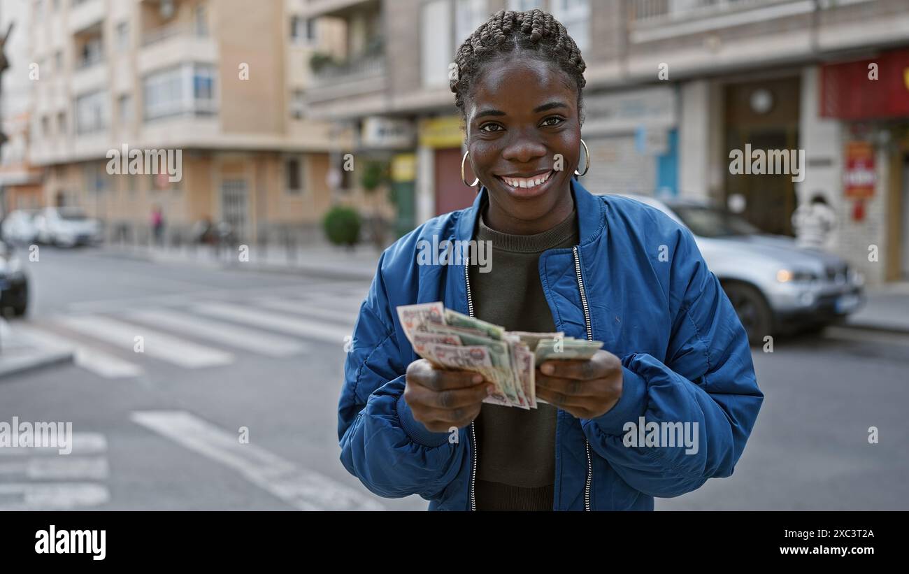 Smiling african woman with braids holding dirhams on an urban street ...