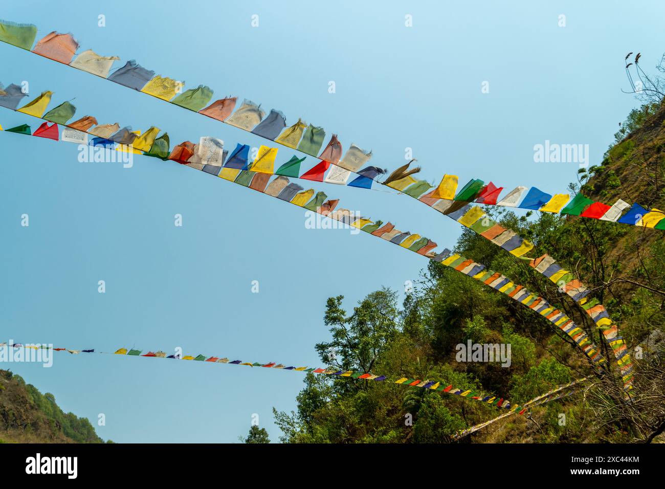 Footage of colorful prayer flags fluttering in Uttarakhand mountains. Windy afternoon. Blue sky. Himalayan landscape. Spiritual tradition. Mountain sc Stock Photo