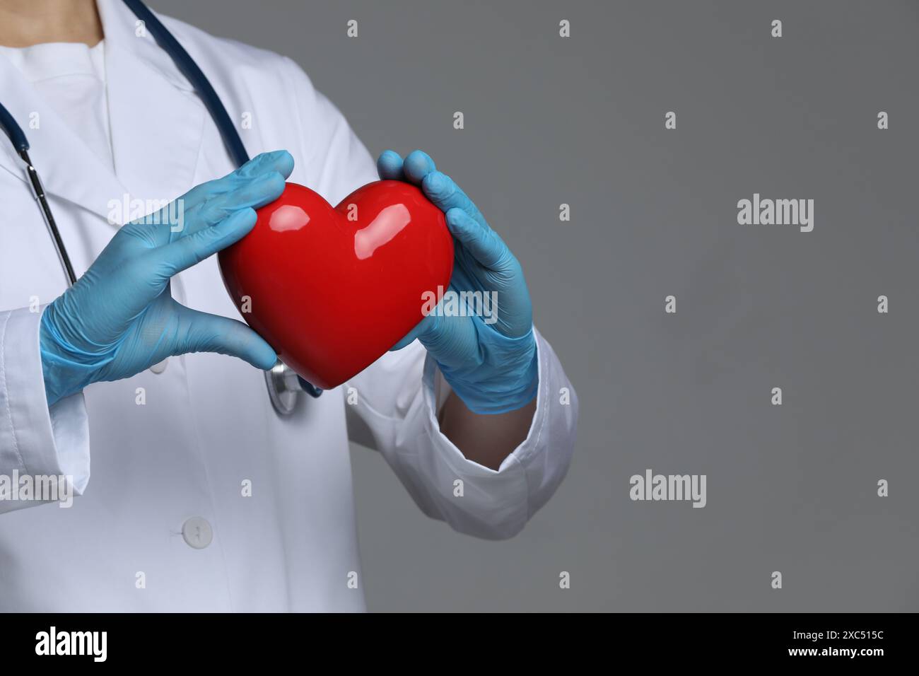 Doctor with red heart on grey background, closeup. Space for text Stock ...