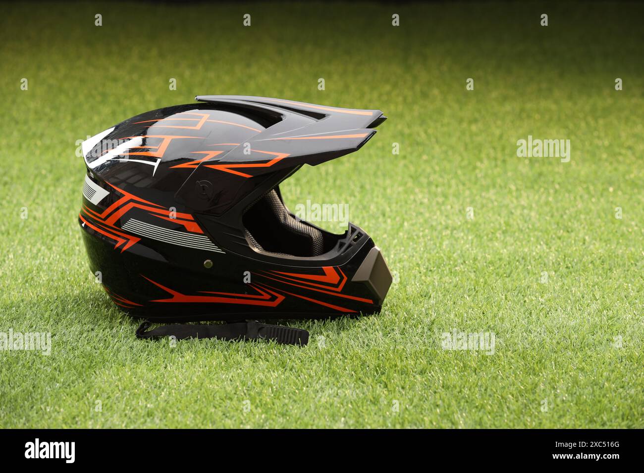 Modern motorcycle helmet with visor on green grass, space for text ...