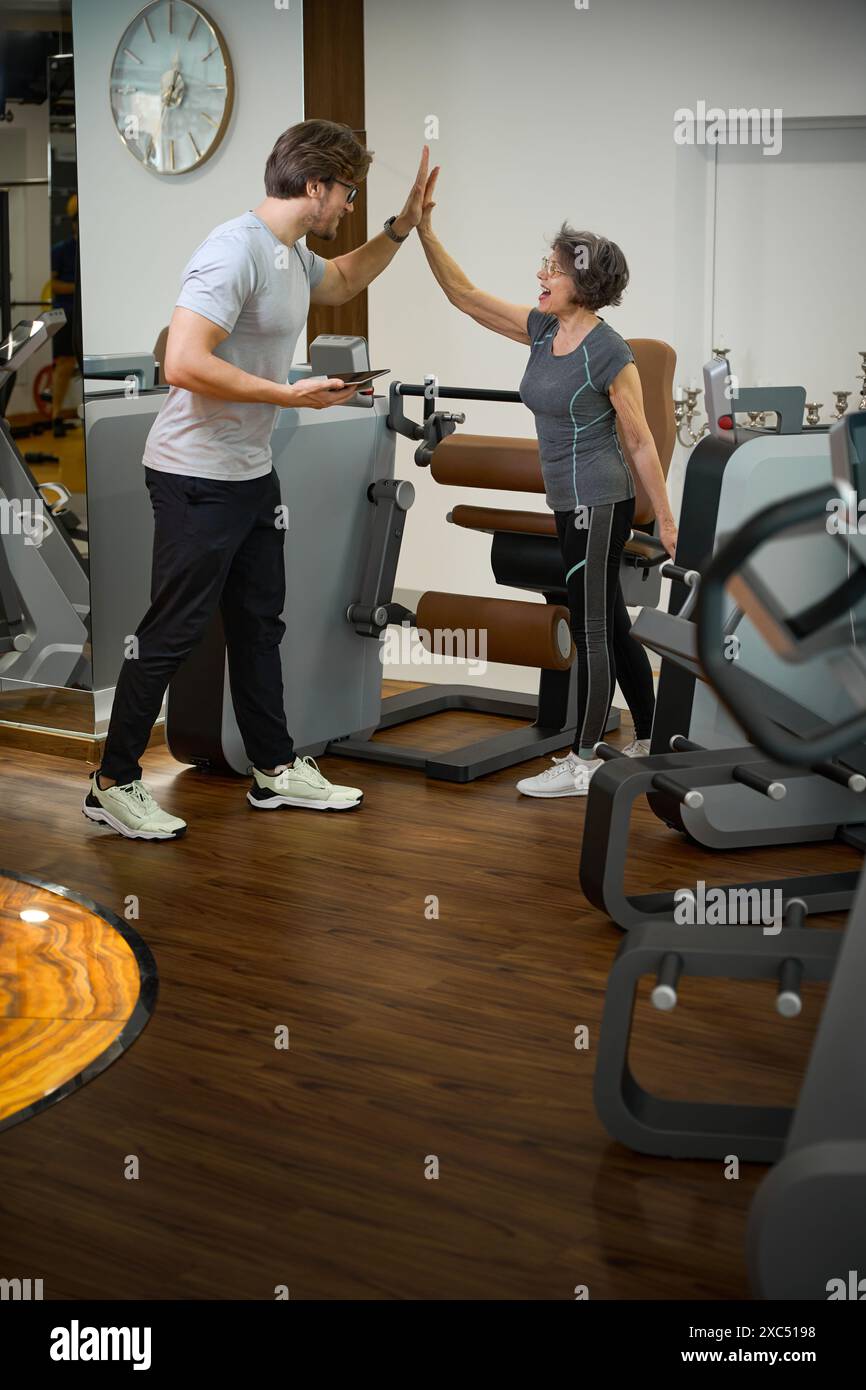 Trainer greets elderly lady in the gym of fitness clinic Stock Photo ...