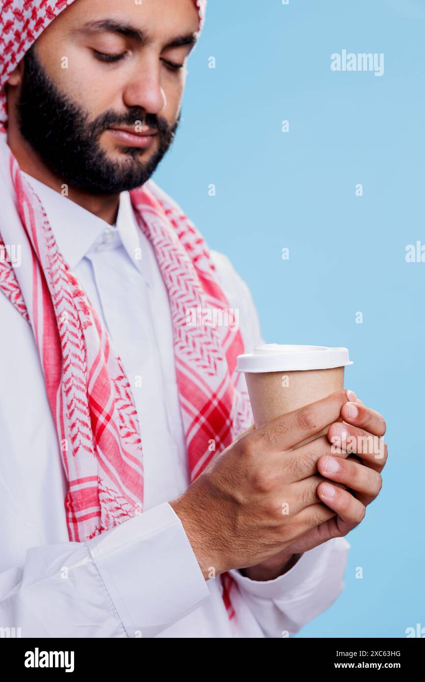 Muslim man with closed eyes holding coffee to go paper mug and 