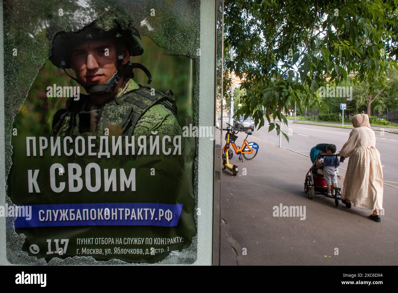 Moscow, Russia. 14th June, 2024. A woman stands at a bus stop next to ...