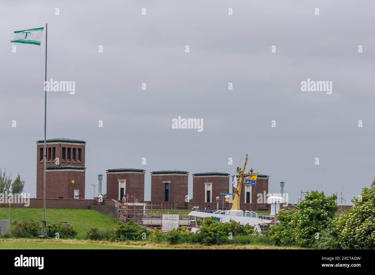 Building with flag, construction work and green grass under a grey sky, dangast, varel, germany Stock Photo