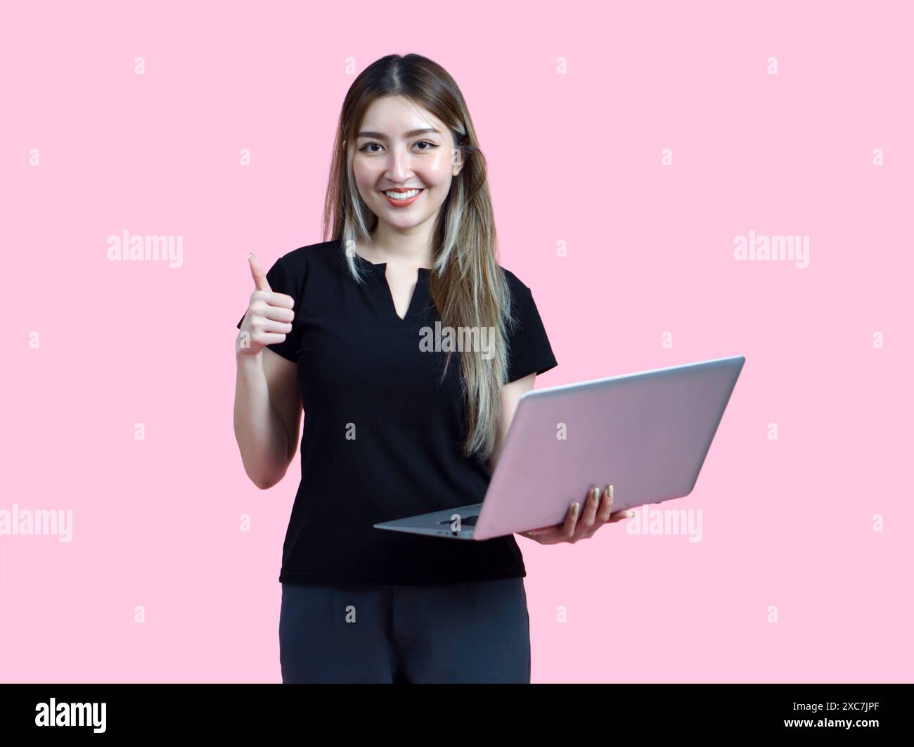 Young asian woman stand with a thumbs up, smile while holding laptop ...