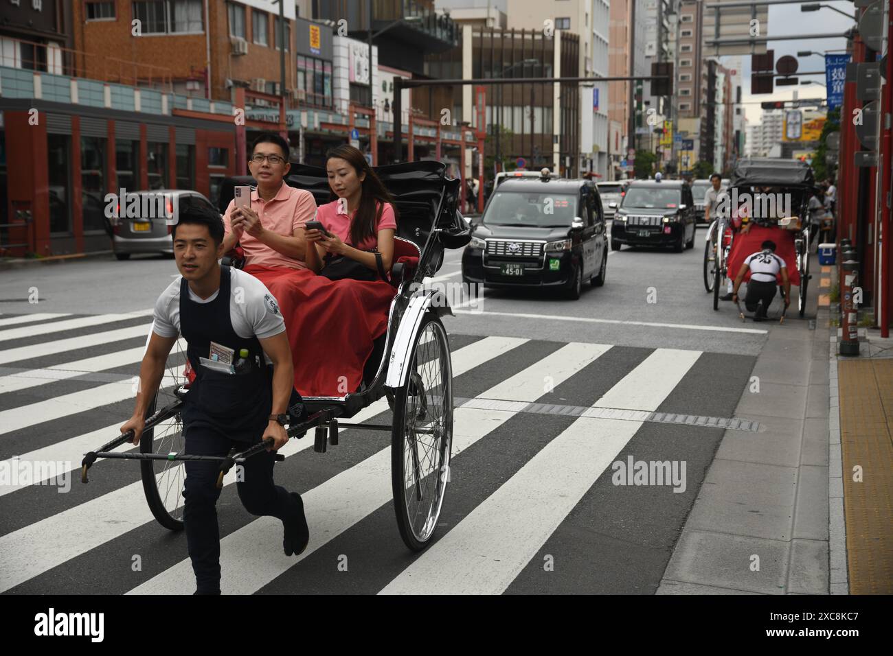 Japanese man carrying a typical japanese rickshaw with tourists on the ...