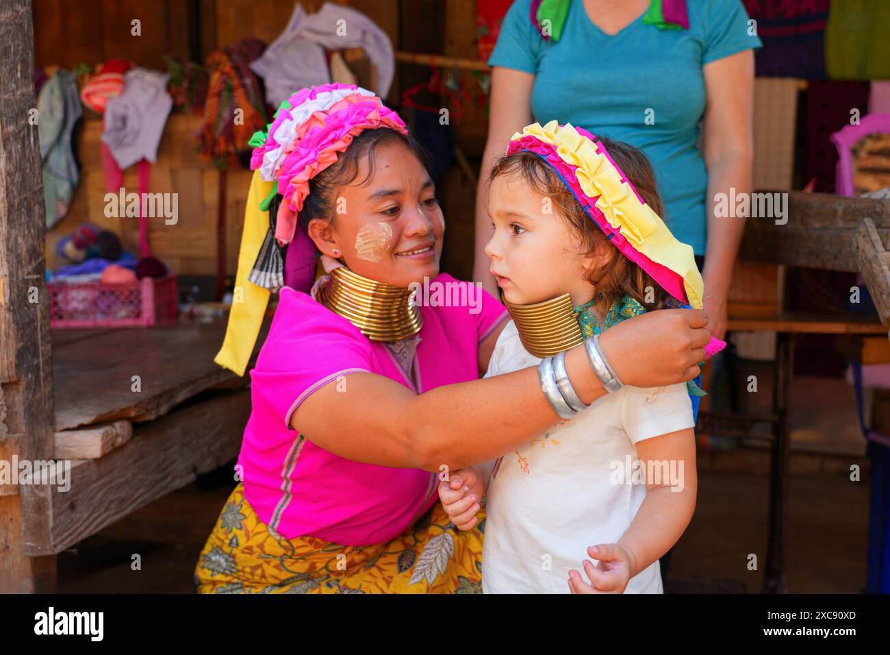 Kayan long-neck woman wearing brass neck rings giving a fake necklace to a European toddler in the Huay Pu Keng ethnic village in the Mae Hong Son pro Stock Photo