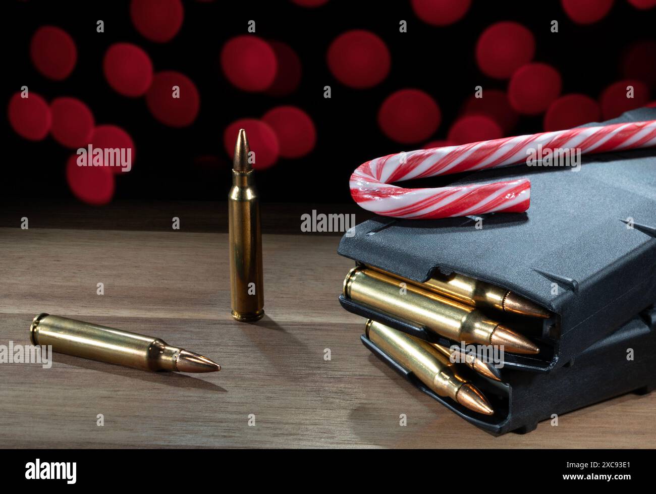 Red Christmas lights behind fully loaded high-capacity AR-15 magazines, and bullets with a candy cane that make an ideal gift for any gun owner on som Stock Photo