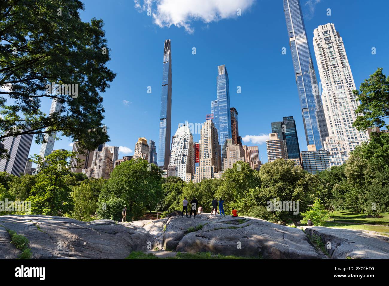 New York City summer morning in Central Park with granite rock formations and view of Billionaires' Row supertall skyscrapers. Midtown Manhattan Stock Photo