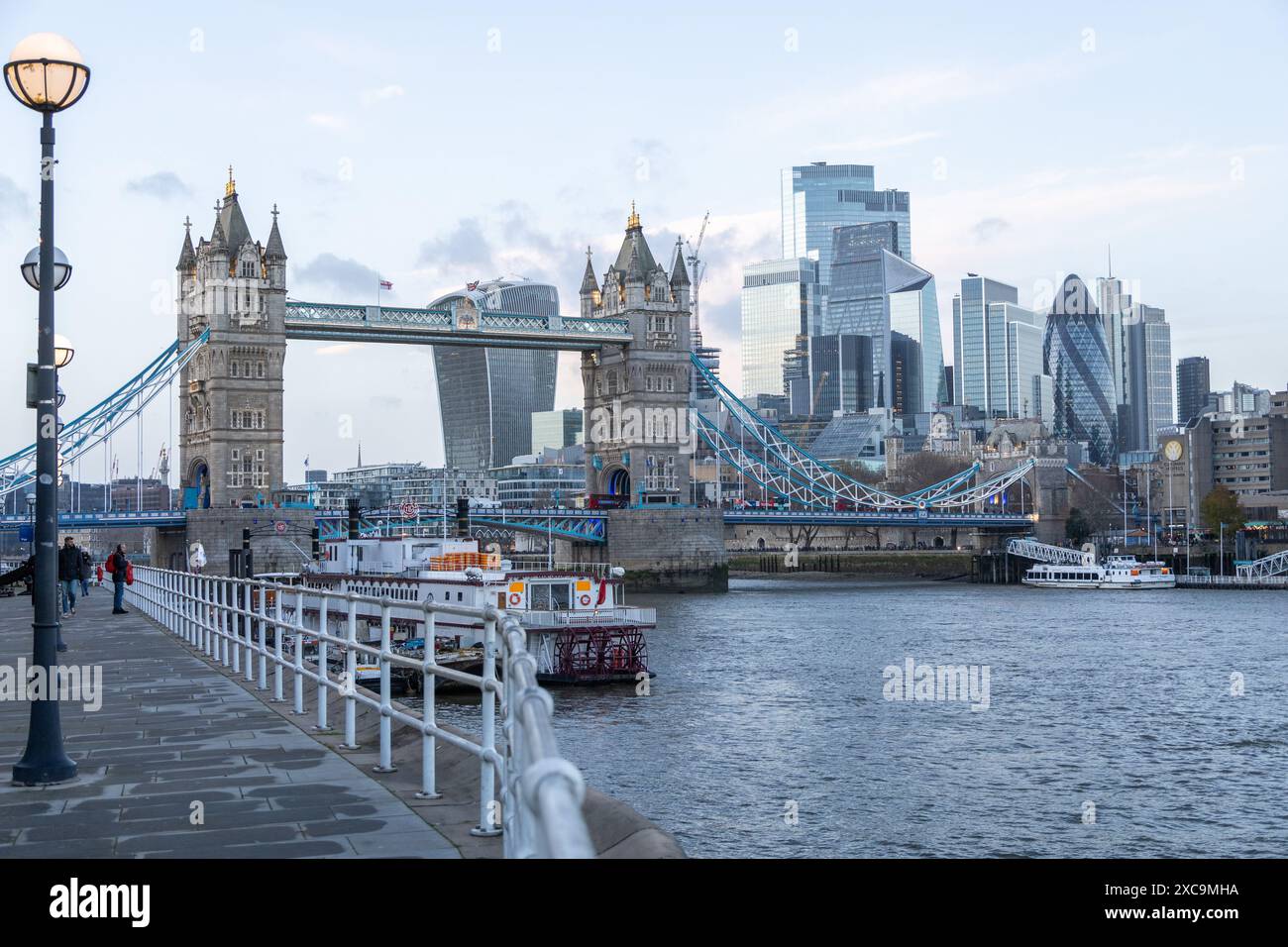 View of Tower Bridge and City of London Skyline taken from Butler’s Wharf Pier area.  Incidental people walking along the pier. Stock Photo