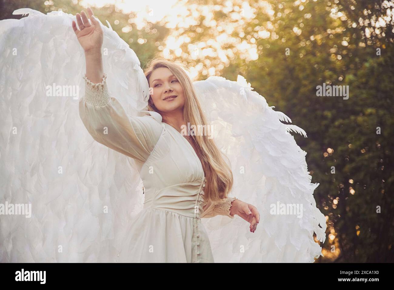 Beautiful girl dressed as an angel in the evening garden Stock Photo