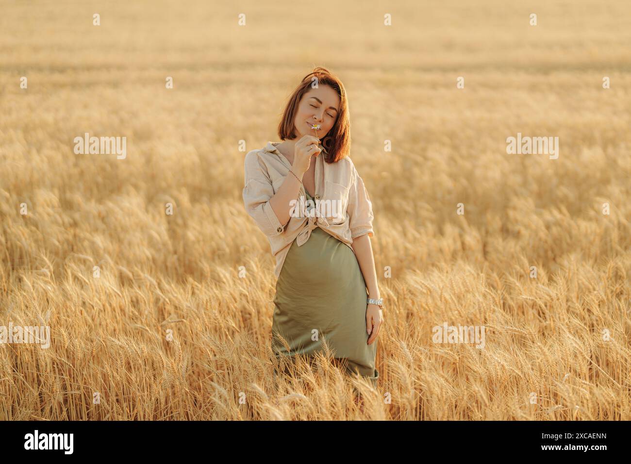 Woman enjoying a serene walk in golden wheat field Stock Photo - Alamy