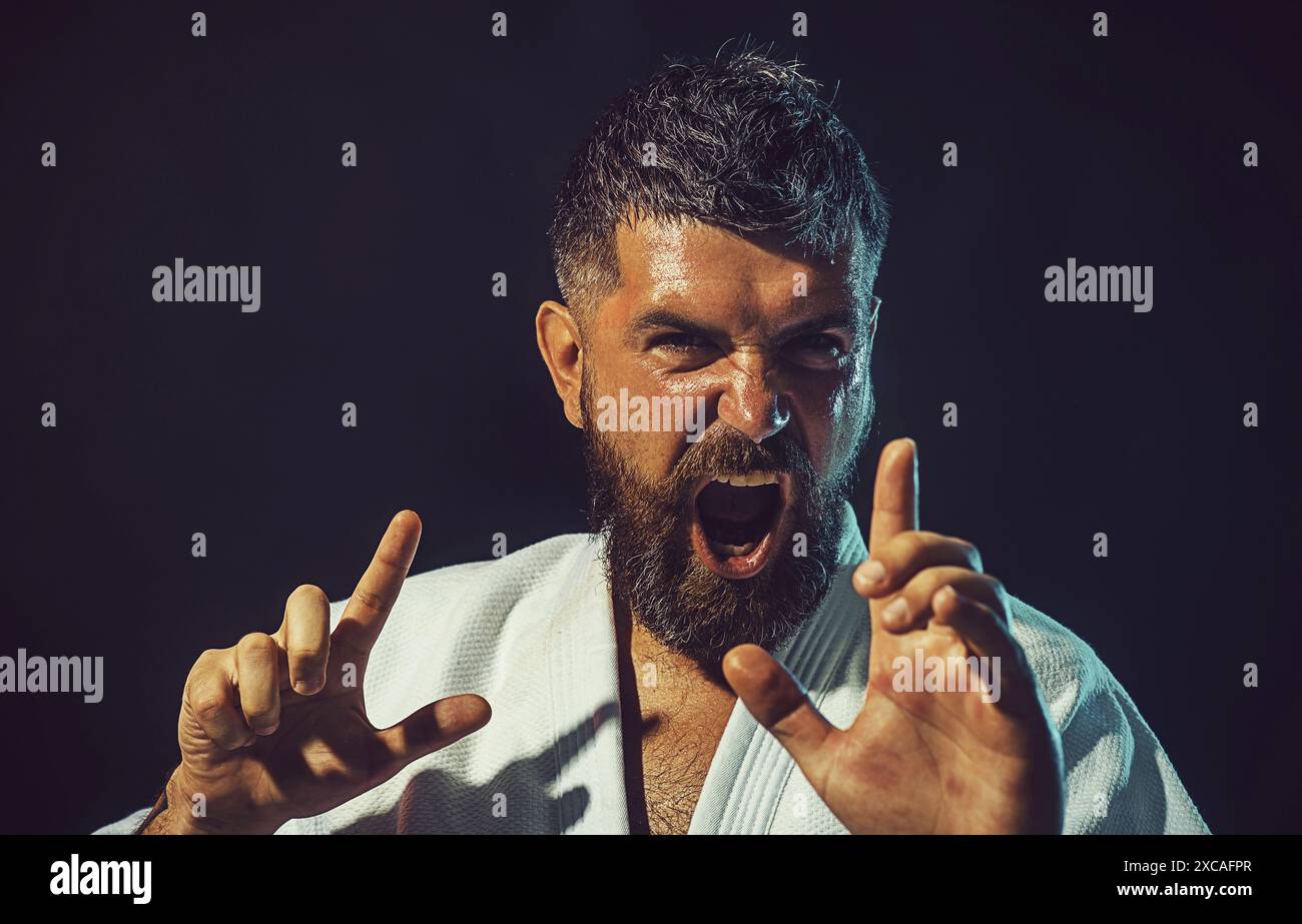 Closeup portrait screaming karate man in fighting position ready for training. Angry male karate instructor in kimono for judo practicing martial arts Stock Photo
