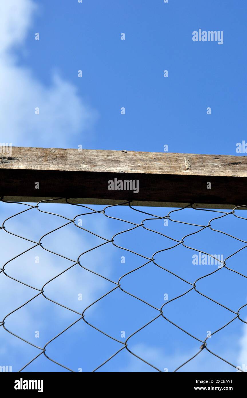 Wire fence with wooden frame blue sky background Stock Photo