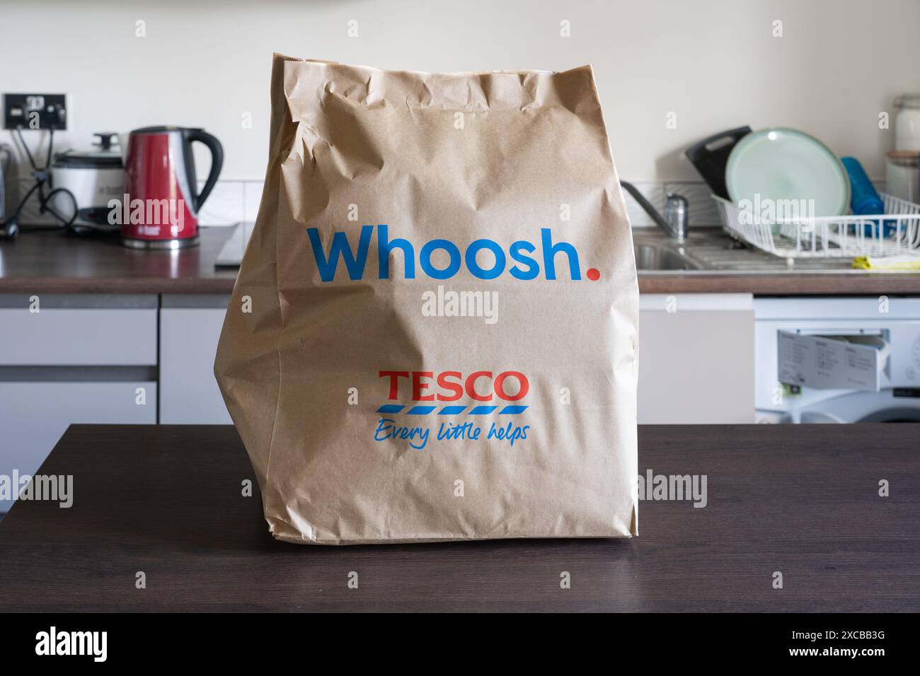 Whoosh paper bag full of groceries on a home kitchen counter - a Tesco supermarket brand for same day home delivery from Tesco Express. England Stock Photo