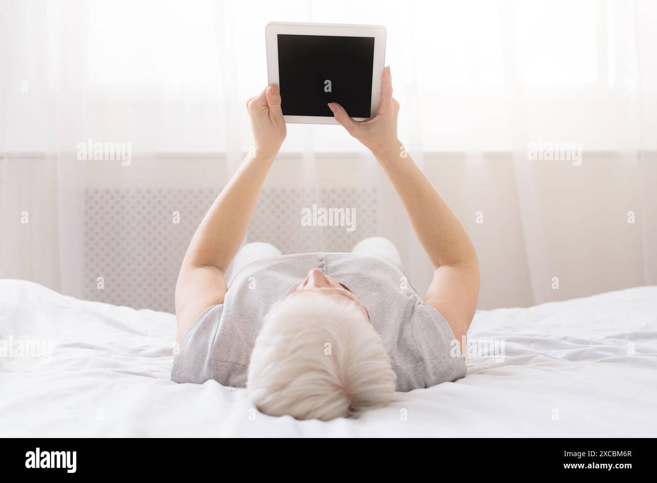 Person Laying on Bed With Tablet with Blank Screen Stock Photo
