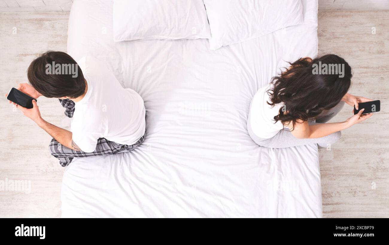 Couple Using Smartphones on Bed, Top View Stock Photo