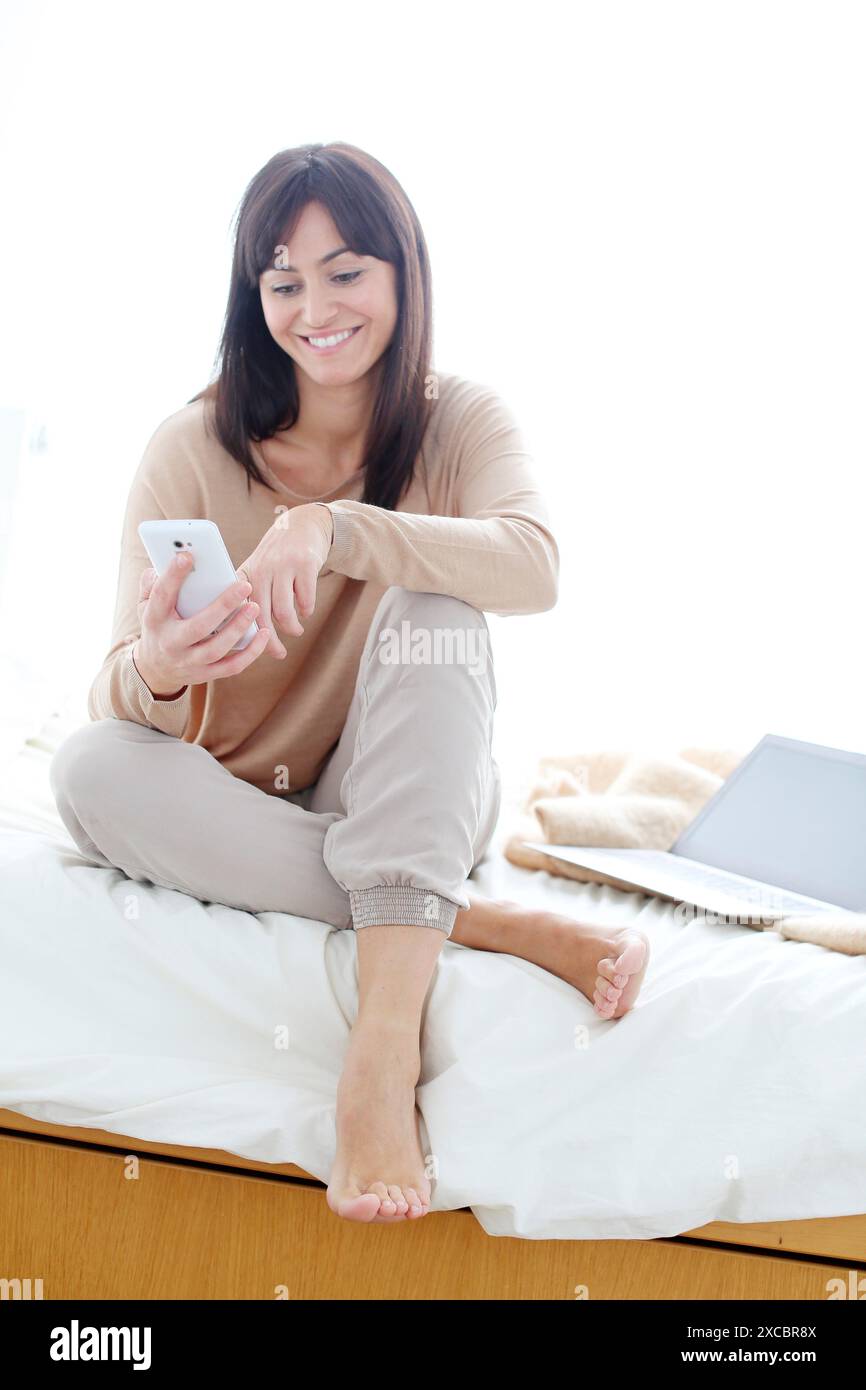 Woman using smartphone and smiling Stock Photo
