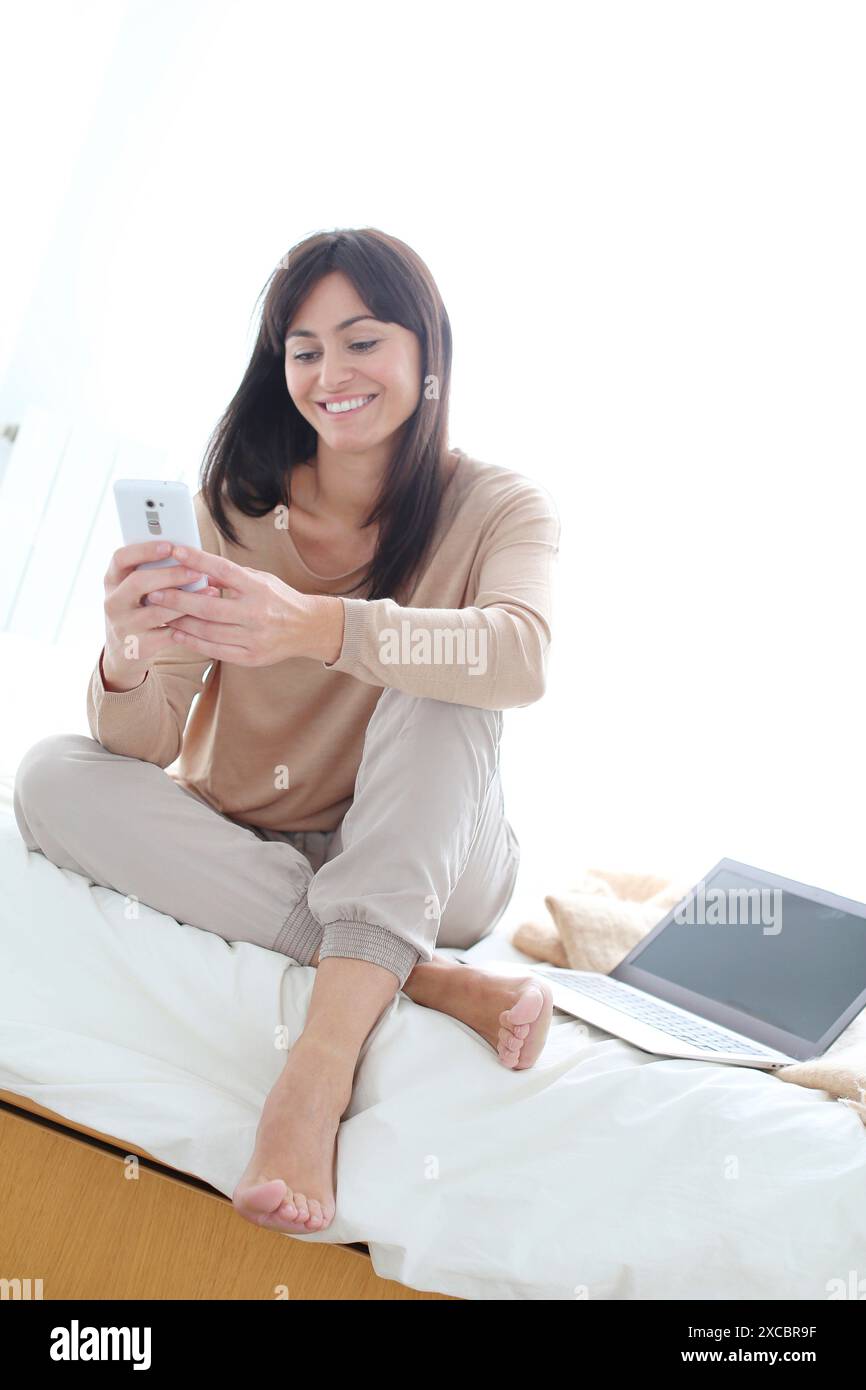 Woman using smartphone and smiling Stock Photo