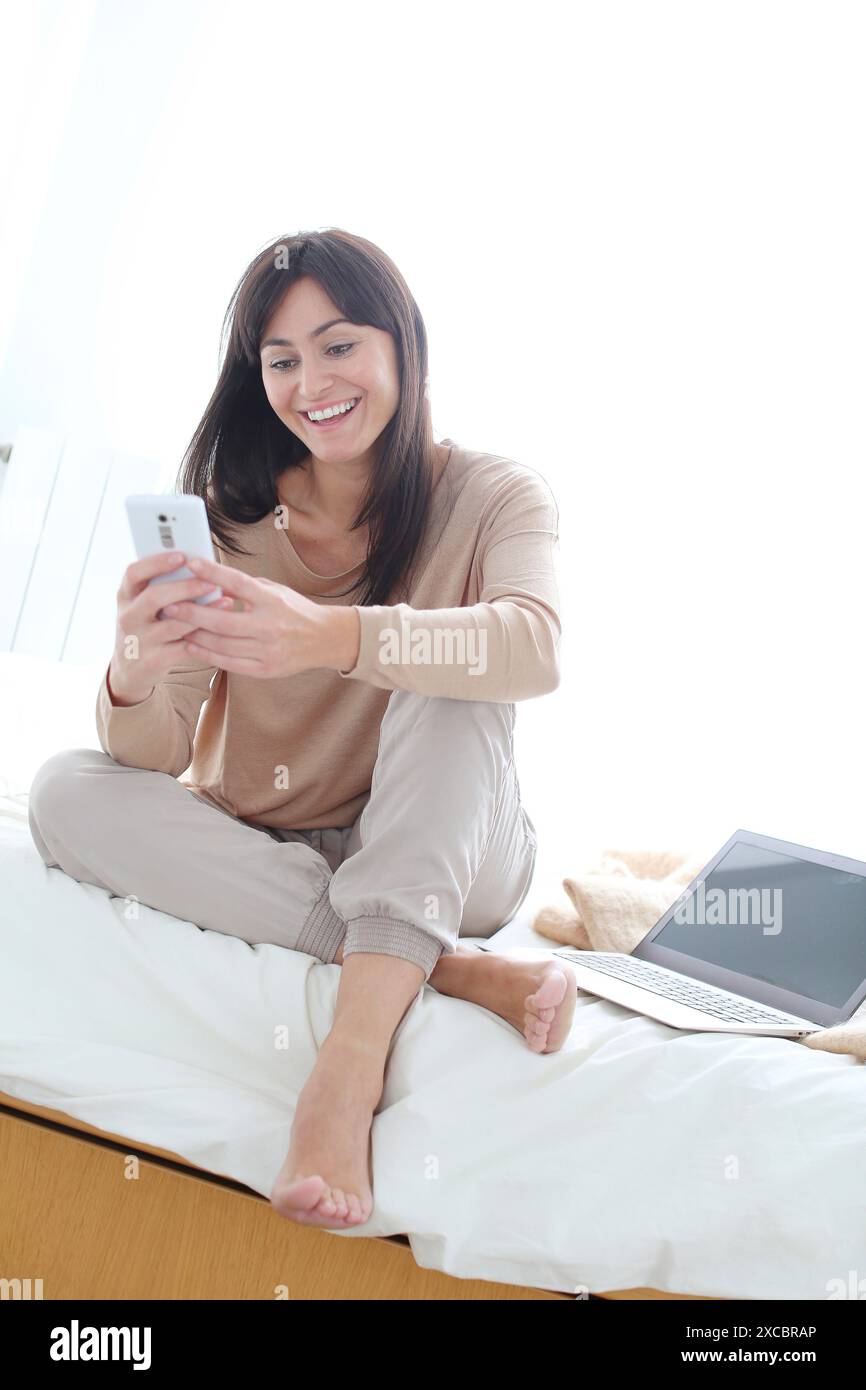 Woman using smartphone and smiling Stock Photo