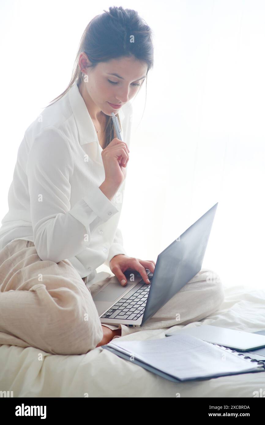 Woman sitting on bed and using  laptop Stock Photo