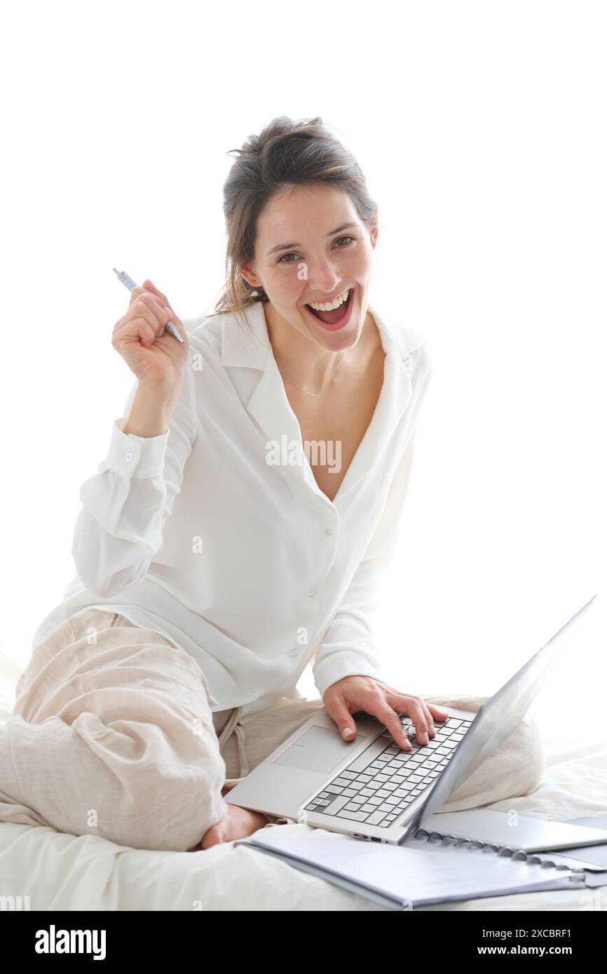Woman sitting on bed and using laptop Stock Photo