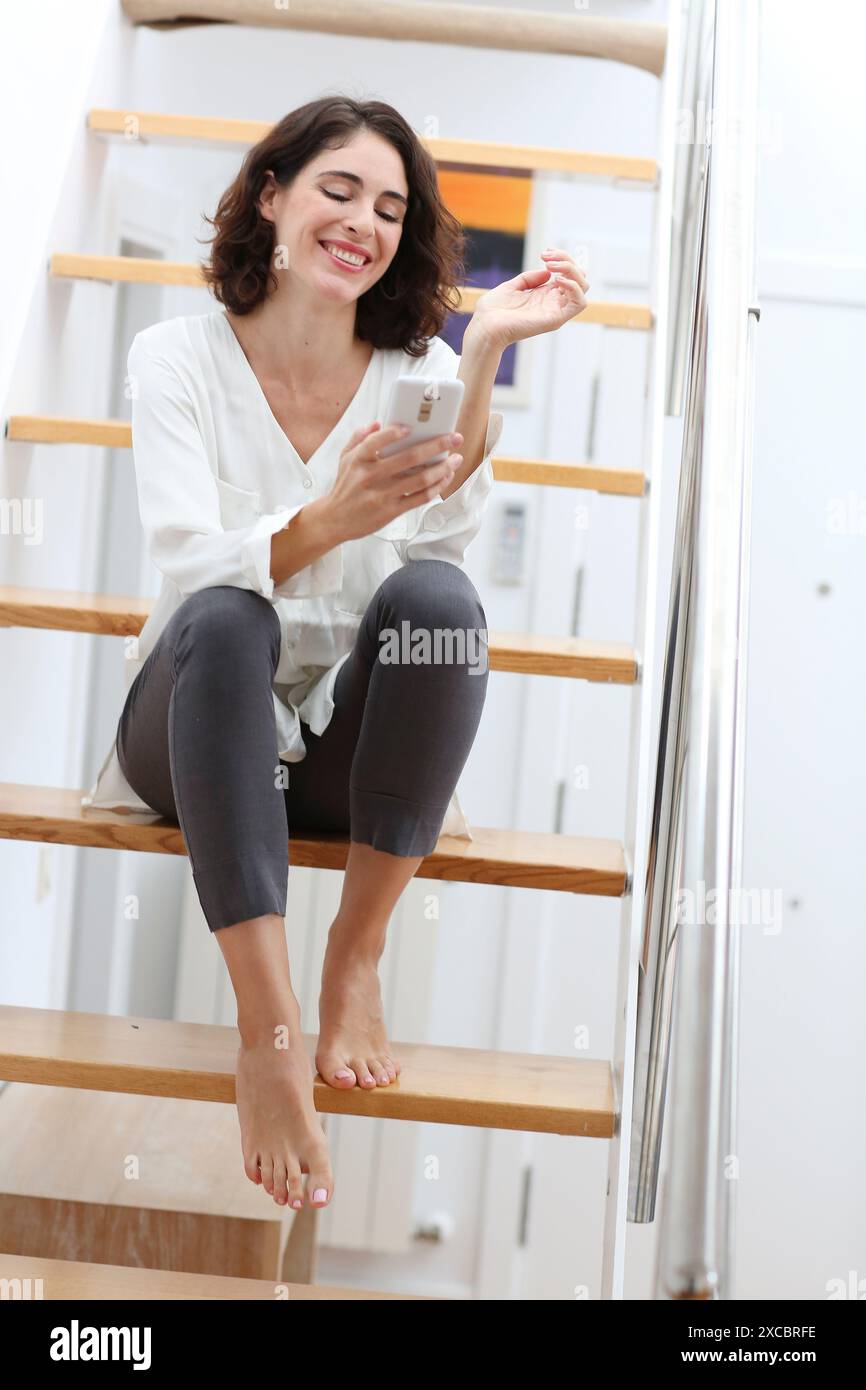 Woman sitting on stairs and using smart phone Stock Photo